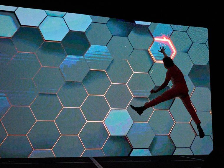 Un bailarín salta sobre una pantalla con un patrón de hexágonos iluminados, en la apertura del Silver Economy Forum.