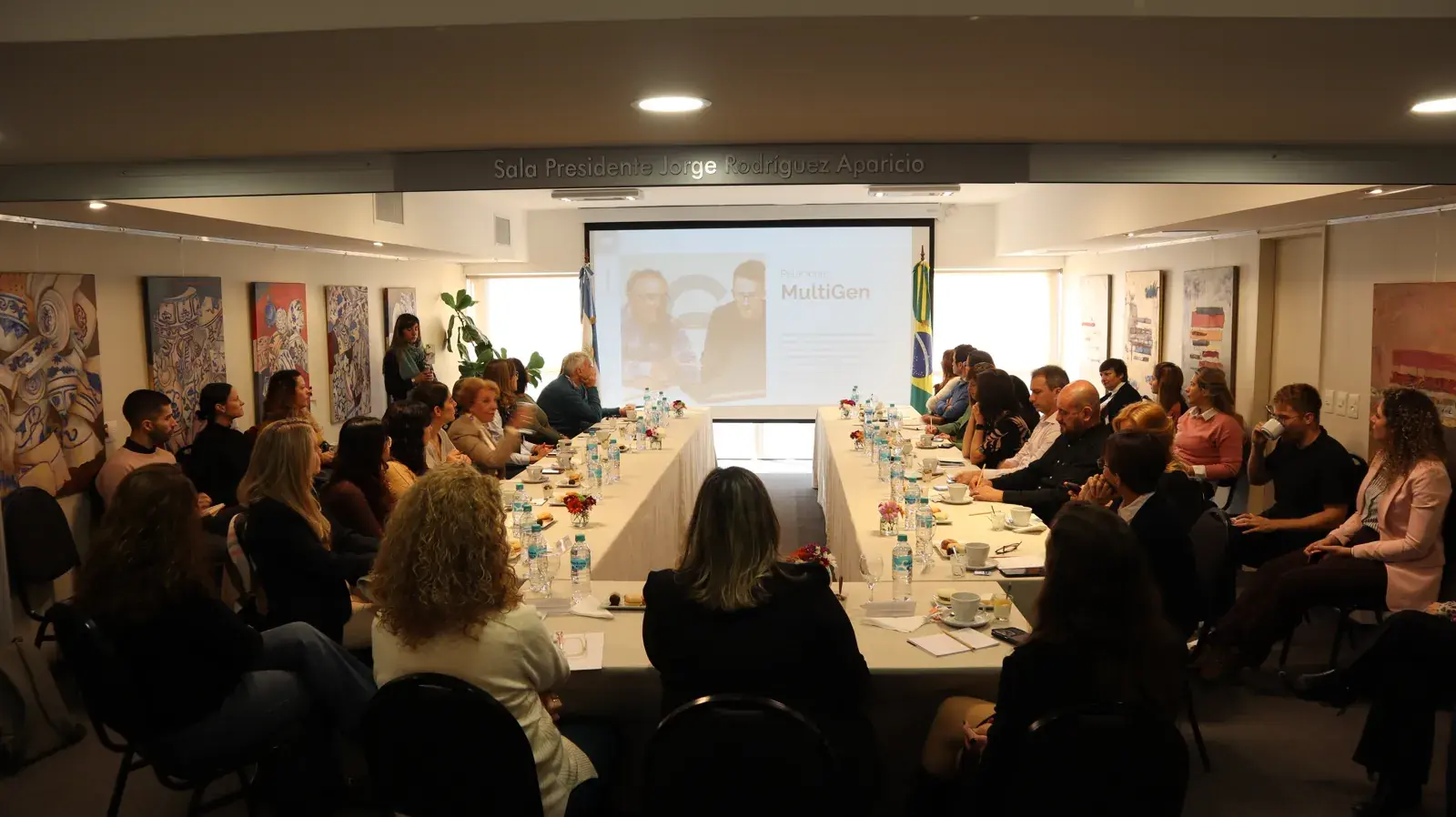 Encuentro de líderes en la Sala Presidente Jorge Rodríguez Aparicio, con una presentación sobre relaciones multigeneracionales (MultiGen) proyectada en pantalla.