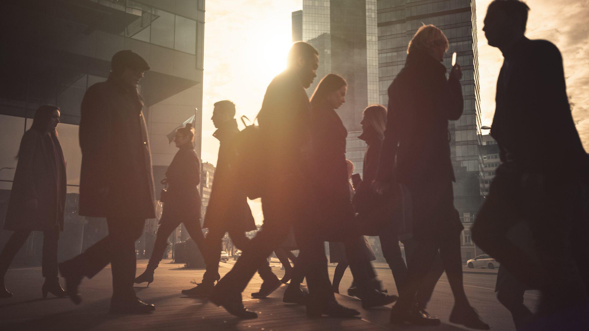 Personas caminando frente a rascacielos al atardecer, símbolo del cambio demográfico