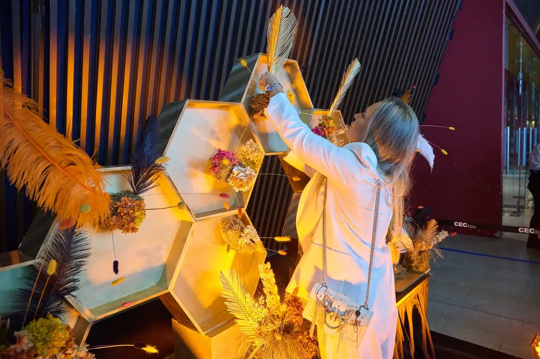 La artista floral Belén Lozano interviene la instalación de panales dorados.